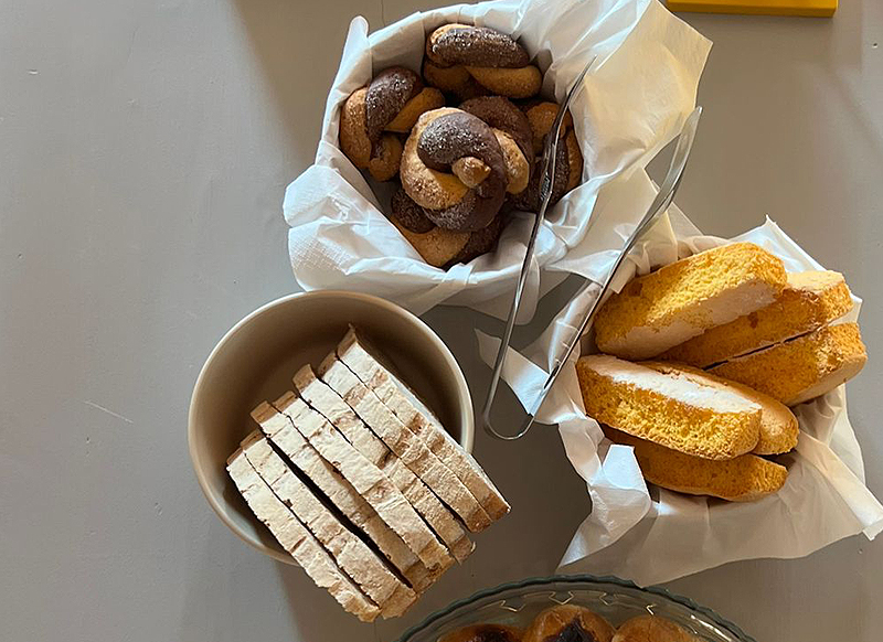 Colazione con biscotti artigianali, fette di pane e ciambelle rustiche