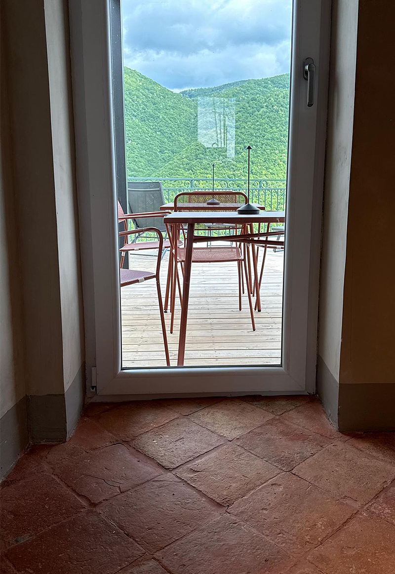 Tavolino sulla terrazza visto dall’interno con sedie rosse